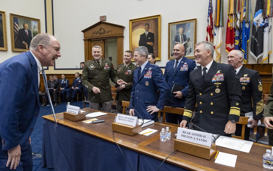 A group of men standing around a table laughing.