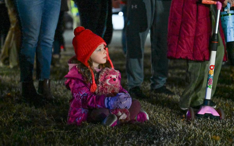 A child wears a red hat and holds a stuffed animal.