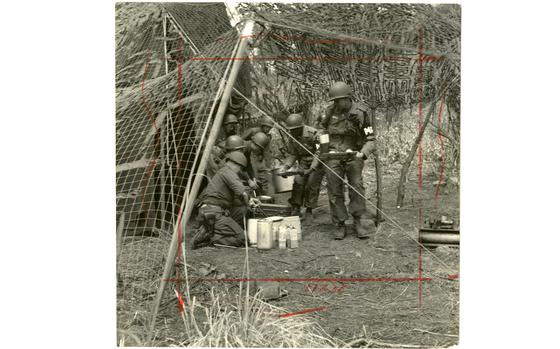 A group of MP's grabs a bite of chow, protected by camouflage netting, while on field assignment. The 7th Military Police Company (Prov.) - the Army's first pentomic MP company - was on a five-day field exercise with the 7th Infantry Division, pulling guard duty and local road patrols in the battle-scarred mountains of north-central South Korea.

Pictured here is a scan of the original 1958 print created by Stars and Stripes Pacific's photo department to run in the print newspaper. The red marks indicate the crop lines. Only the middle part of the image would appear in the newspaper. As the vast majority of pre-1964 Stars and Stripes Pacific negatives and slides were unwittingly destroyed by poor temporary storage in 1963, the prints developed from the late 1940s through 1963 are the only images left of Stripes' news photography from those decades – with the exception the negatives of some 190 pre-1964 photo assignment found recently. Stars and Stripes' archives team is scanning these prints and negatives to ensure their preservation. 

Looking for Stars and Stripes’ historic coverage? Subscribe to Stars and Stripes’ historic newspaper archive! We have digitized our 1948-1999 European and Pacific editions, as well as several of our WWII editions and made them available online through https://starsandstripes.newspaperarchive.com/

META TAGS: 7th Infantry Division; U.S. Army; Military Police; MP; servicemember; pentomic; training; exercise; Northwind; combat MP training; military life; meal; food; cooking; African American