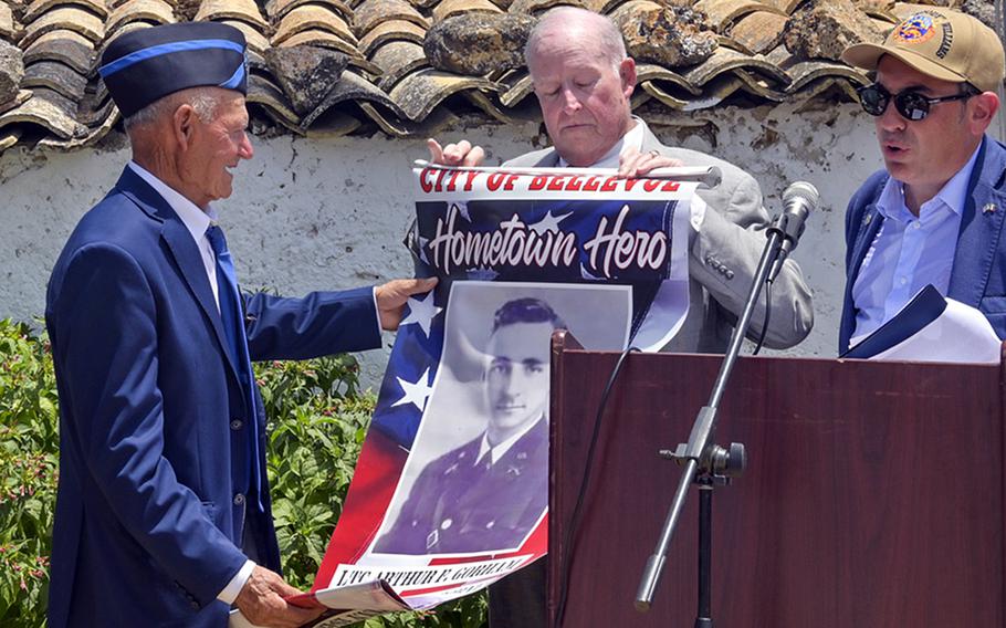 Retired Army Col. Bruce Clark, son of Lt. Col. Arthur Gorham, one of the service members who was killed in action during Operation Husky, presents a hometown heroes flag at the 82nd Airborne Division Monument at Ponte Dirillo in Gela, Italy, July 10, 2023. 