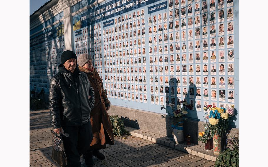 Photos of fallen Ukrainian and foreign soldiers and volunteers are displayed on a wall outside St. Michael's Cathedral in Kyiv. 