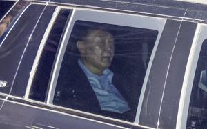 The South Korean president is sitting inside a car and seen through the window with his eyes closed.