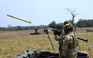 Two soldiers launch a bright yellow FIM-92D Stinger missile.