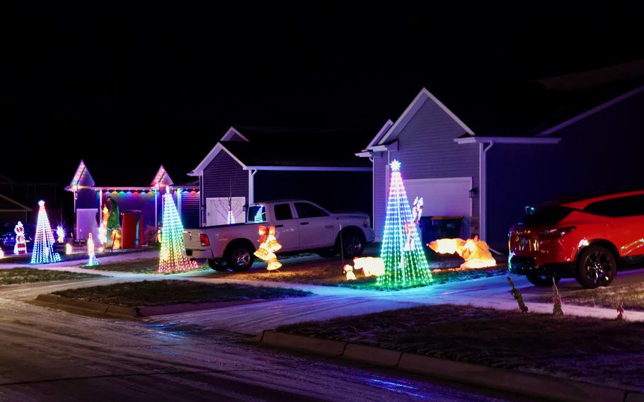 A row of homes decorated for Christmas in John Reichart’s neighborhood, each one with a 9-foot, cone-shaped light string tree in front. 