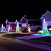 A row of homes decorated for Christmas in John Reichart’s neighborhood, each one with a 9-foot, cone-shaped light string tree in front. 