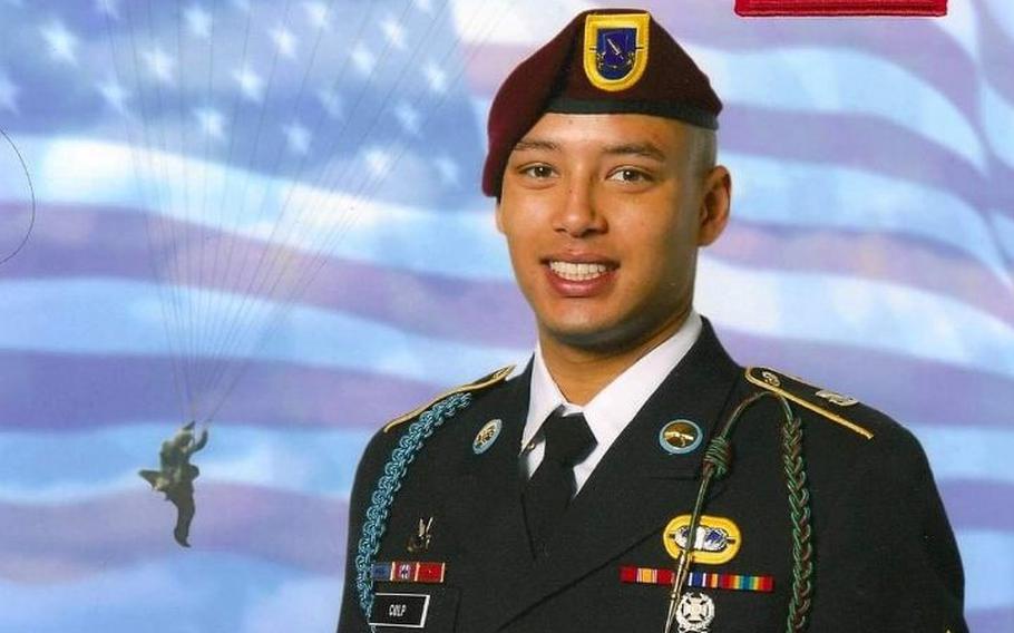 A soldier in dress uniform with a U.S. flag background.