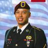 A soldier in dress uniform with a U.S. flag background.