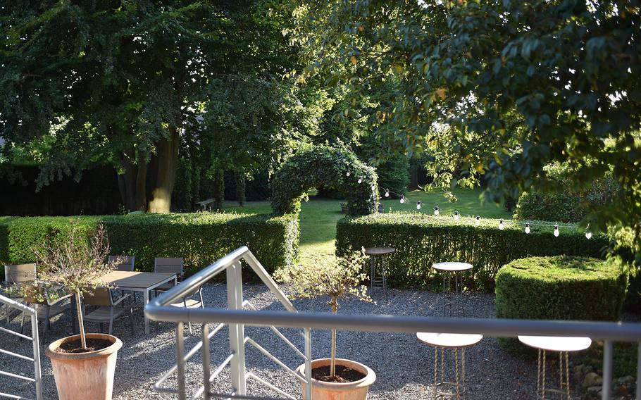 Behind the main seating areas of L'intuition in Houdeng-Aimeries, Belgium, is an arched bush that leads to a green space. The restaurant can host banquets and other parties.