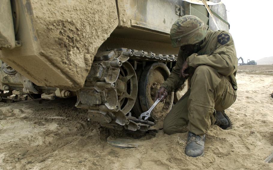 Army Pfc. Tamelle Hil tries to repair a broken track