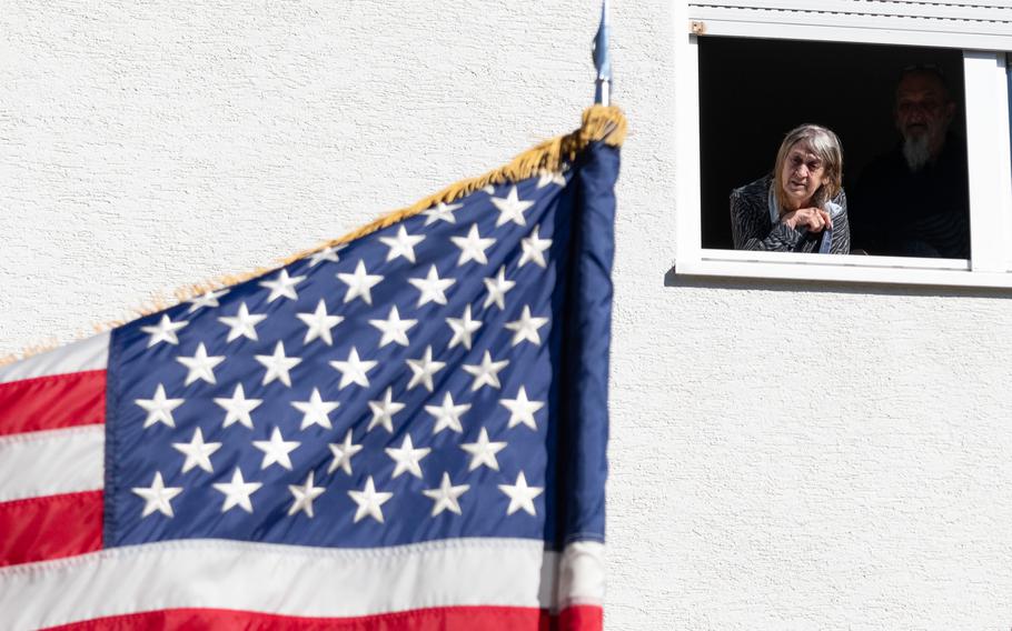 A woman looks down from a window at a U.S. flag