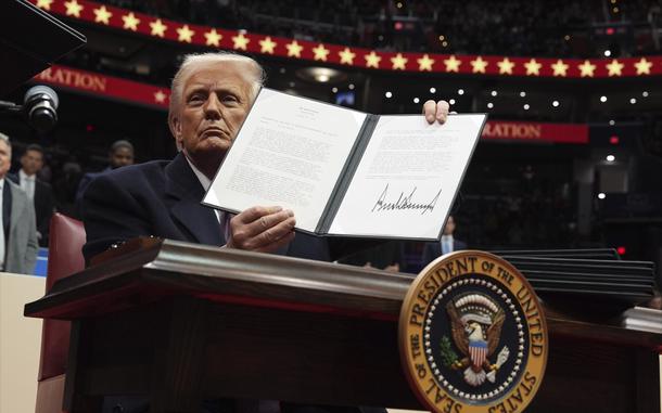 President Donald Trump shows a signed executive order.