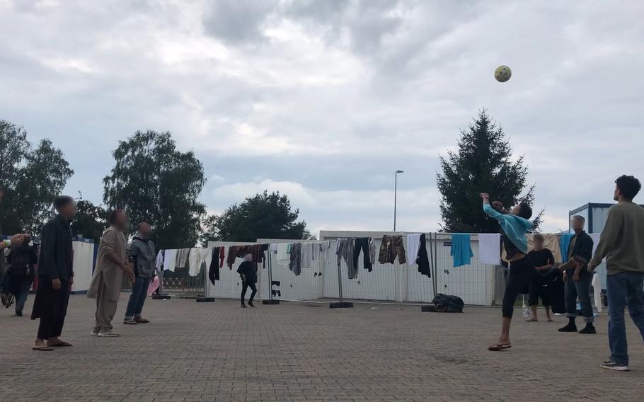 Afghan men play volleyball without a net in a concrete courtyard at Rhine Ordnance Barracks in Germany.