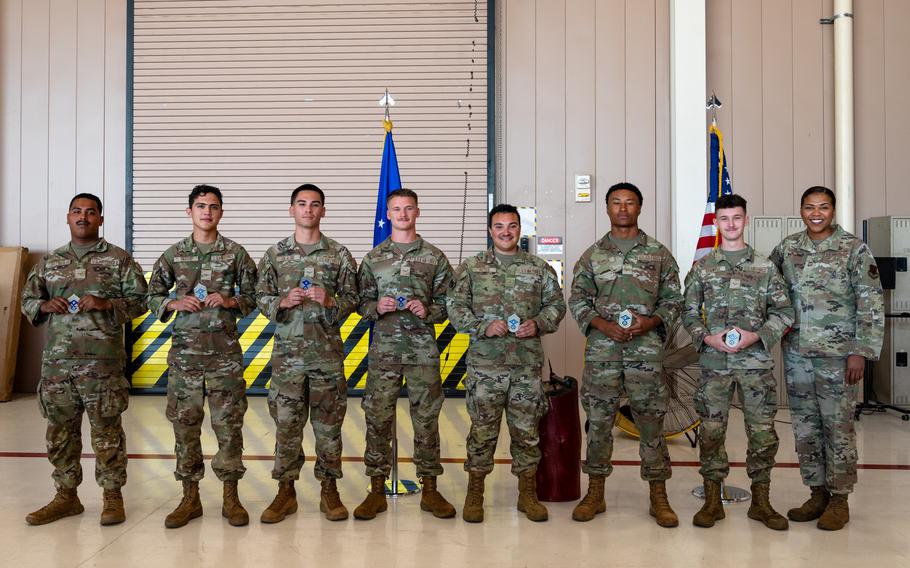 Airmen pose with coins during a ceremony at Nellis Air Force Base, Nevada, Aug. 26, 2024. Airmen saved the lives of a pregnant woman and her companions during a flash flood in Zion National Park earlier this month. From left are Airmen 1st Class Rony Lopez-Aguilar, Airmen Andres Parra, Airmen 1st Classes Maximos Olade and Will Martin, Airmen Christian Reyes, and Airmen 1st Classes Demarcus Norman and Jacob Stillwell. At far right is Chief Master Sgt. Adrienne Warren, the chief master sergeant of the 99th Air Base Wing.