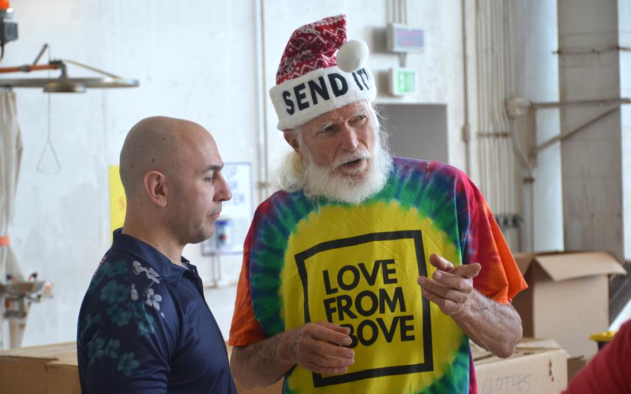 Bruce Best, also known as “Brother Bruce,” discusses Operation Christmas Drop with a volunteer at Andersen Air Force Base on Dec. 7, 2024. 