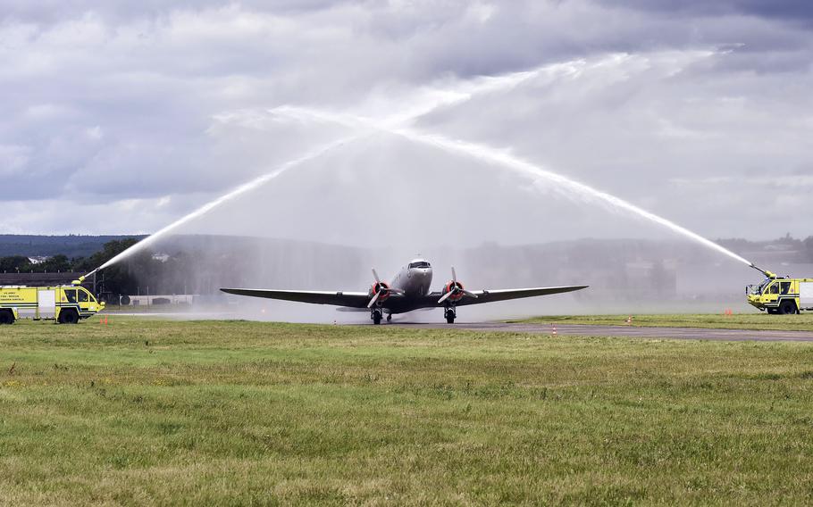 A Douglas C-47 Skytrain taxis underneath a water cannon salute 