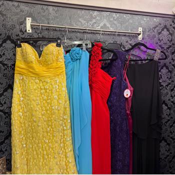 Row of six different colored dresses hanging in a dressing room