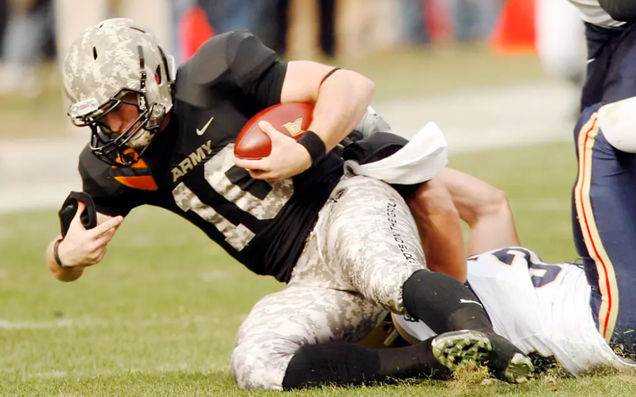 An Army player is tackled by a Navy player.