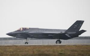 A pilot lands a strike fighter aircraft on a tarmac.