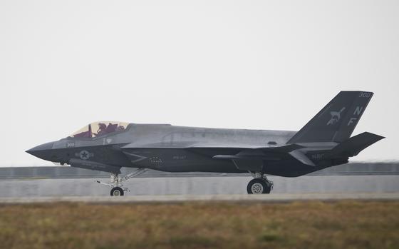 A pilot lands a strike fighter aircraft on a tarmac.