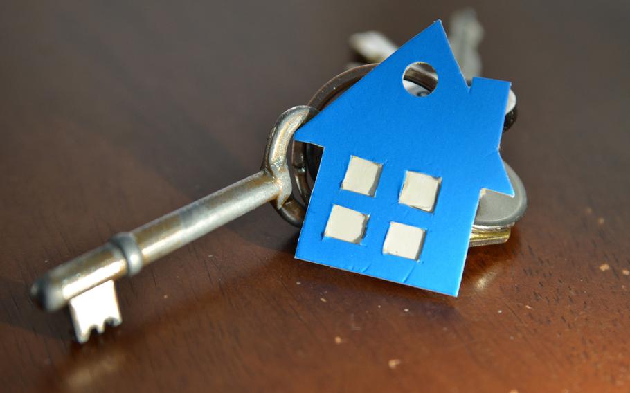 Key with keychain in the shape of a house on a wooden background