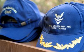 Command ball caps sit on display prior to a ribbon cutting ceremony for Naval Leadership and Ethics Center (NLEC) in Newport, R.I., with Rear Adm. Walter E. "Ted" Carter Jr., president, U.S. Naval War College (NWC), and Capt. Mark Johnson, commanding officer, NLEC, at Perry Hall onboard Naval Station Newport. As of May 1, NLEC, formerly known as Command Leadership School, was realigned as an echelon three command under NWC. The NLEC will serve as the Navy and NWC's instrument to provide curriculum development along with assessment to instill fundamental tenets of ethical leadership throughout the Navy; develop and guide leaders with a strong abiding sense of responsibility, authority, and accountability; and impart commitment of Navy Core Values and Navy Ethos to Sailors.