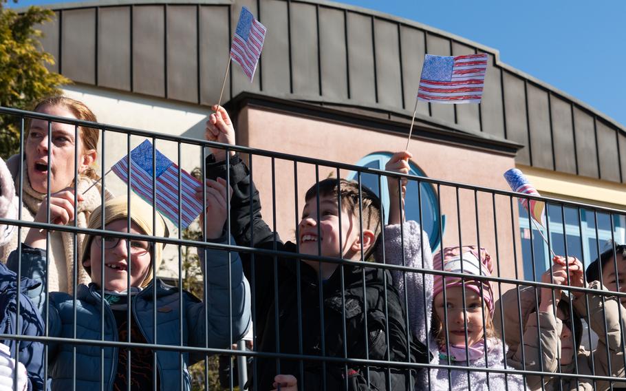 Children wave U.S. flags behind a fence