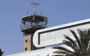 A damaged airport control tower is seen from a distance next to a sign reading Sana’a International Airport.