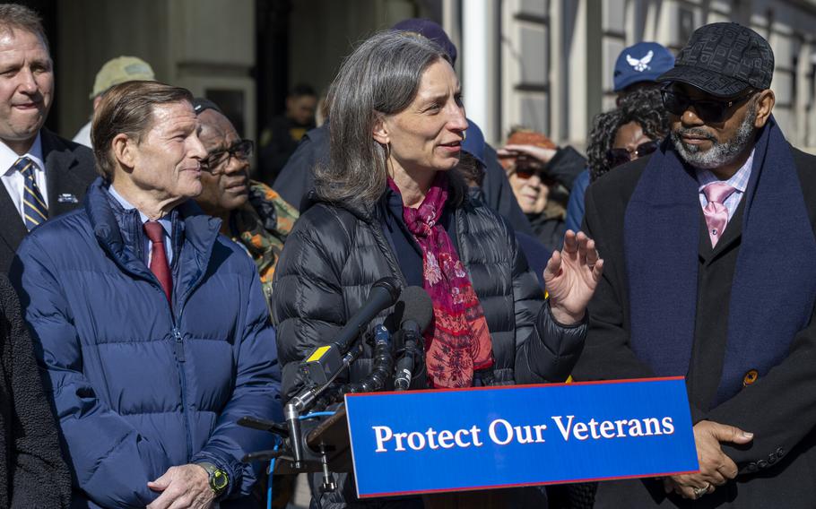 A woman speaks at a podium with people behind her.