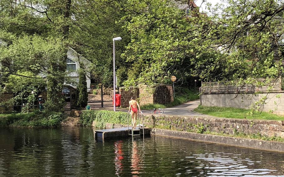 A swimmer cools off with a dip in the Bärenloch in Kindsbach, Germany, on a warm May day. The spring-fed lake is a popular Pfalz swimming spot surrounded by woods with hiking trails.