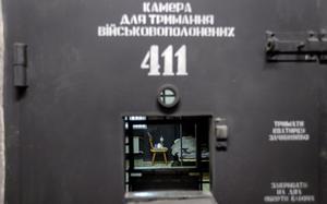 A person is seen lying on a bed from a prison door window.