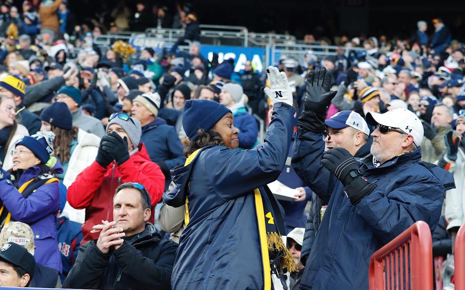 Navy fans high-five in the stands.