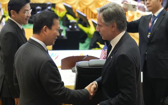 Secretary of State Antony Blinken shakes hands with Cambodian Prime Minister Hun Manet next to a conference table at a diplomatic summit.