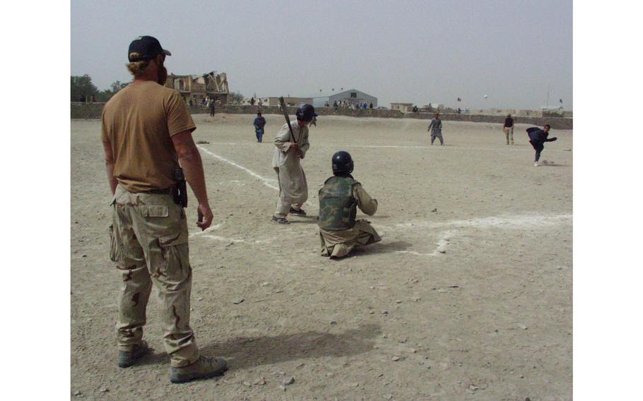 Sgt 1st Class Casey Grau, left, umpires an Afghan baseball game Aug. 16, 2002, in Orgun-e, Afghanistan. U.S. soldiers have put together two baseball teams with local boys, holding games each Friday. 