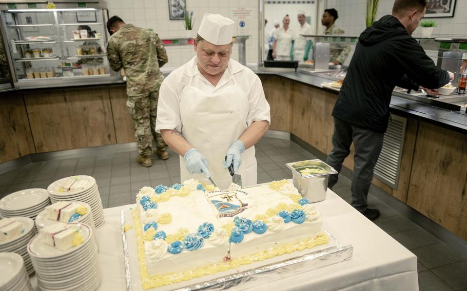 A cake is cut by a dining worker for the 7th Army NCO Academy’s 75th anniversary.