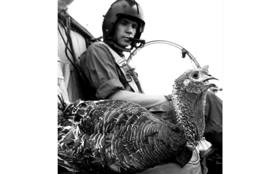 A helicopter pilot glances over at a live turkey in the co-pilot seat.