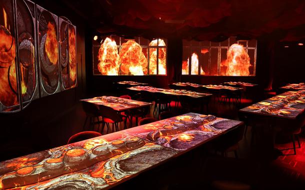 Inside the interior of the Gallery restaurant as fire-themed projections illuminate the tables and walls.