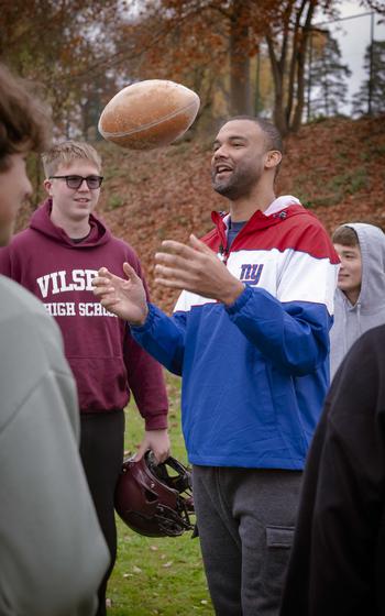 Brandon London, a former wide receiver for the New York Giants, talks to students at Vilseck High School before playing a quick tag football game with them at Rose Barracks, Germany, Nov. 7, 2024. The visit precedes the Giants’ Sunday game against the Carolina Panthers in Munich.