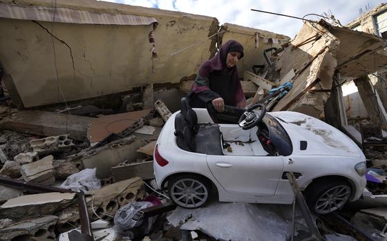 A woman removes a battery-powered ride-on toy car from rubble.