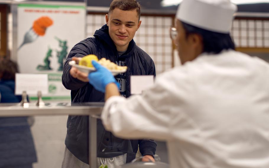 A service member reaching to grab his Thanksgiving meal