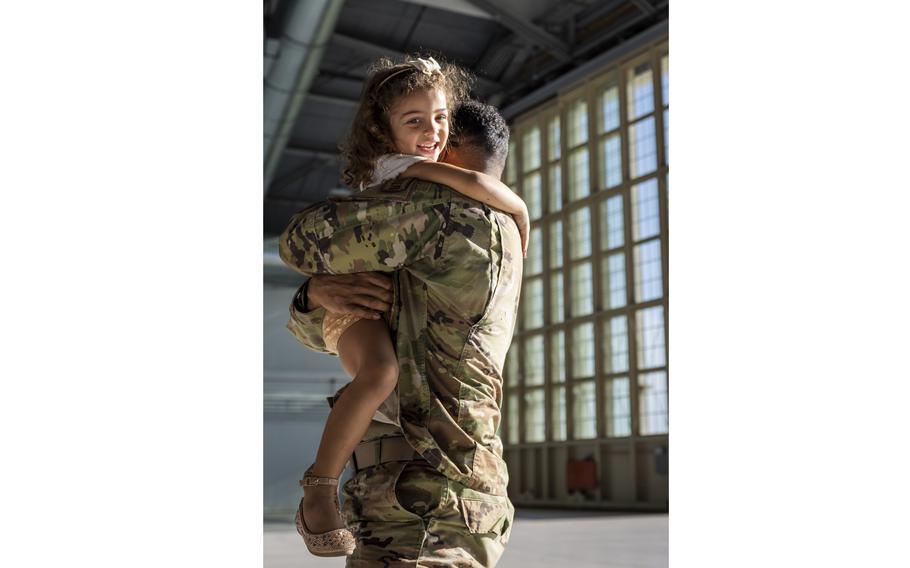 Airman embraces a young girl