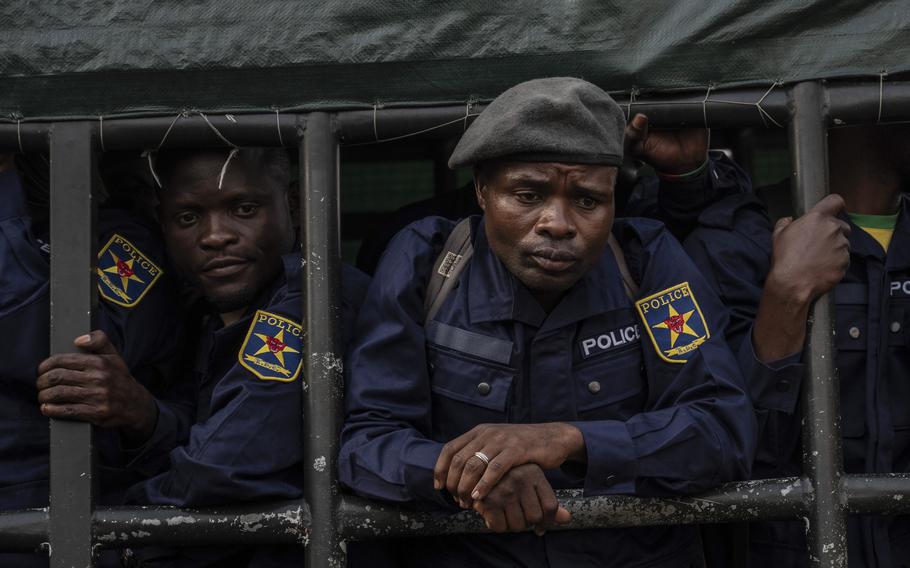 Men with police patches and uniforms look out from a vehicle.