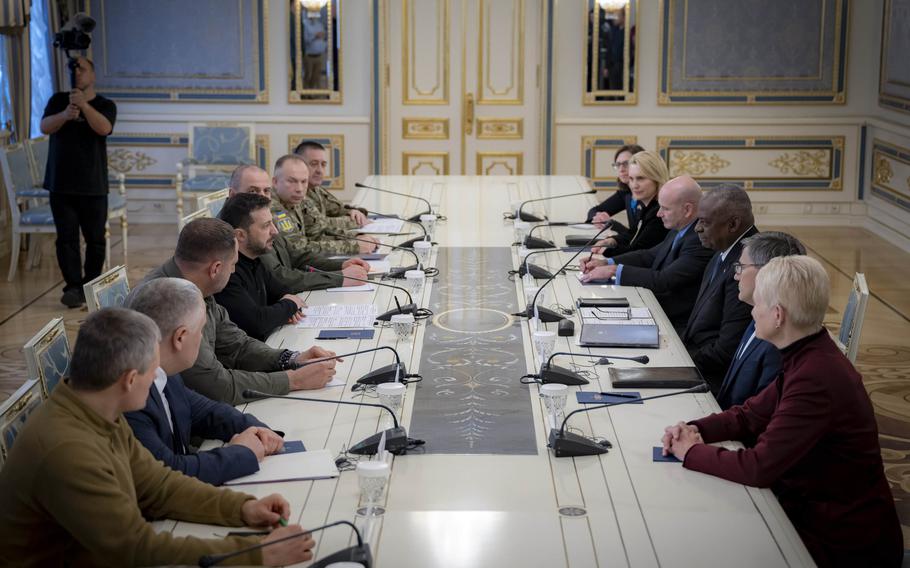 Lloyd Austin, Volodymyr Zelenskyy and other leaders gather around a table during a meeting.