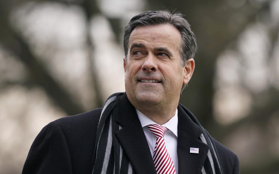 A man in a striped tie and scarf smiles.