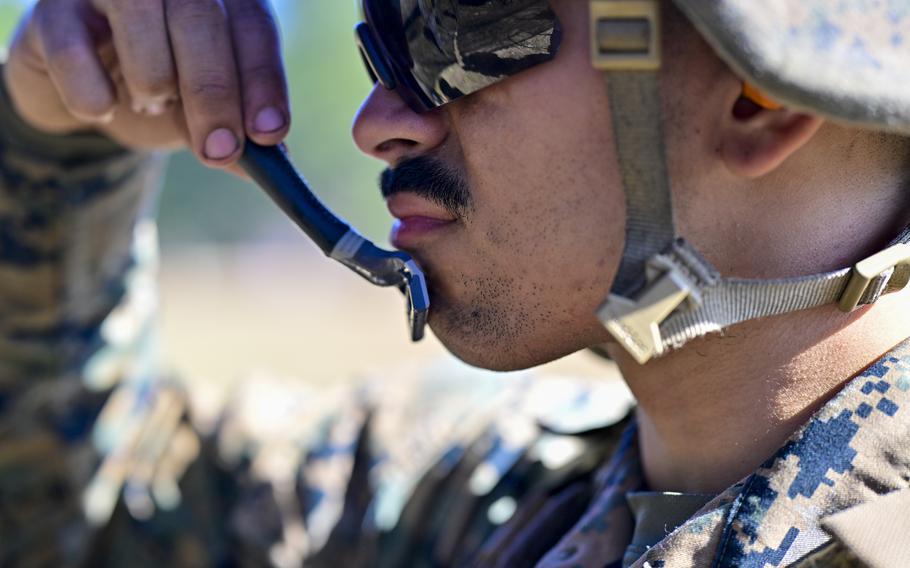 A Marine runs a razor across his chin. 