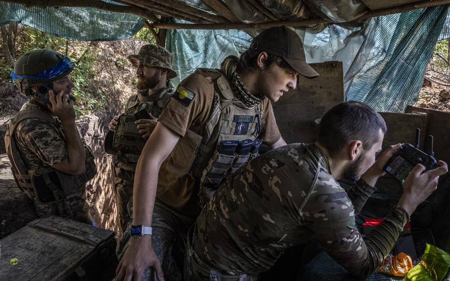 A Russian soldier digging a trench is seen in the video feed from a surveillance drone operated by a soldier with the call sign Honey, right, as a soldier with the call sign Miami, center right, looks on and Chuck, left, speaks to the unit’s commanders in a trench in a tree line belonging to Ukraine’s 78th Assault Regiment, forward from the village of Mala Tokmachka in Zaporizhzhia, Ukraine.