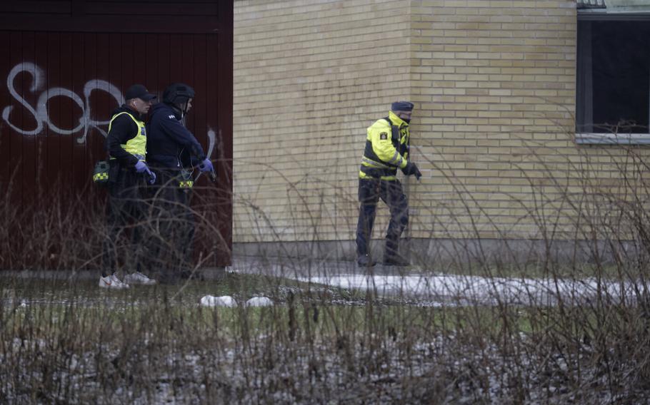 Police officers holding guns wait and look out from the corners of buildings.