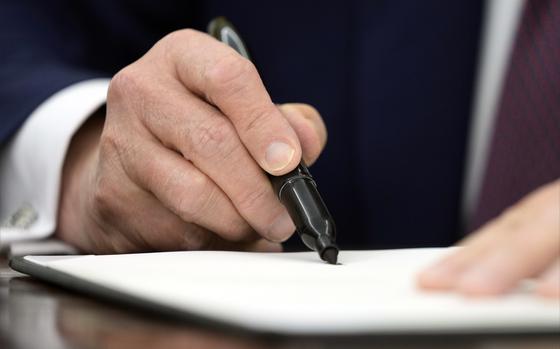 President Donald Trump signs an executive order in the Oval Office of the White House, Thursday, Jan. 23, 2025, in Washington. (AP Photo/Ben Curtis)