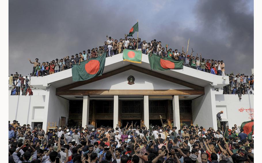 Anti-government protestors display Bangladesh’s national flag as they storm Prime Minister Sheikh Hasina’s palace in Dhaka on Aug. 5, 2024. 