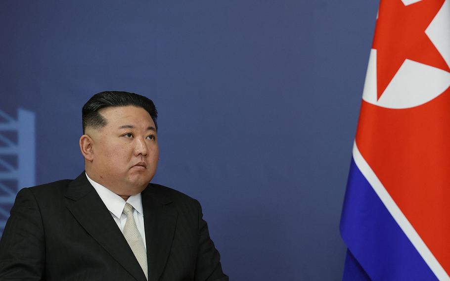 North Korean leader Kim Jong un sits beside the North Korean flag.