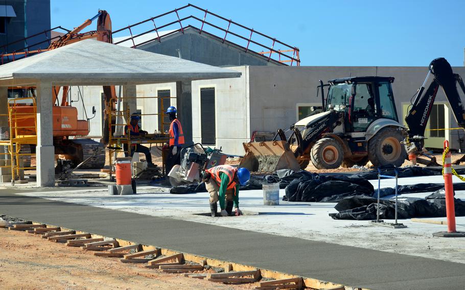 A man wearing a heard hat does cement work.